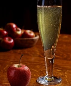 Wine glass of hard cider with apples