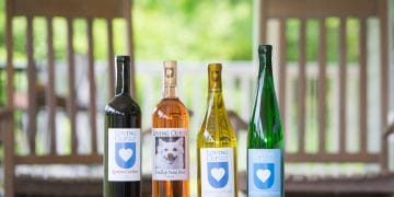 A colorful selection of wines from Loving Cup Vineyard are displayed on a table outdoors