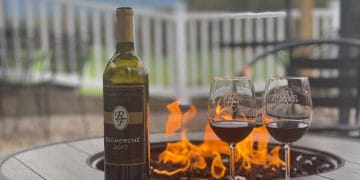 A bottle of wine and two glasses sit alongside the firepit at the Reynard Florence Vineyard